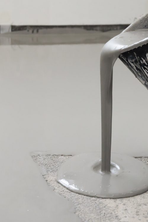 pouring concrete onto a floor from a bucket